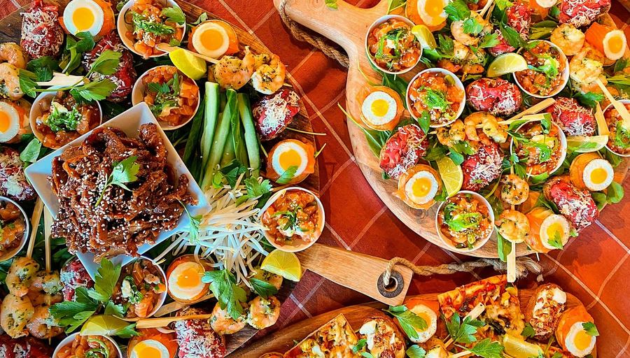 Houten planken vol bites met zalm, kwartelei, tataki en gyoza