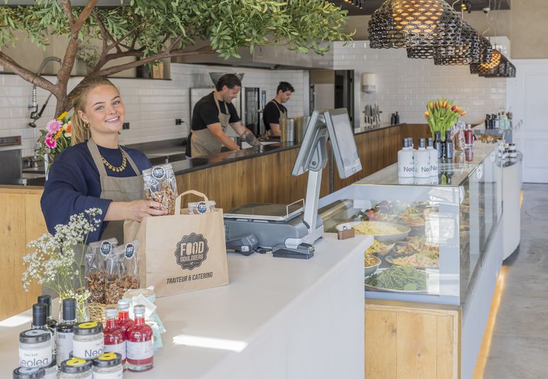 Medewerker van Foodsouldiers pakt een bestelling in, chefs in de open keuken
